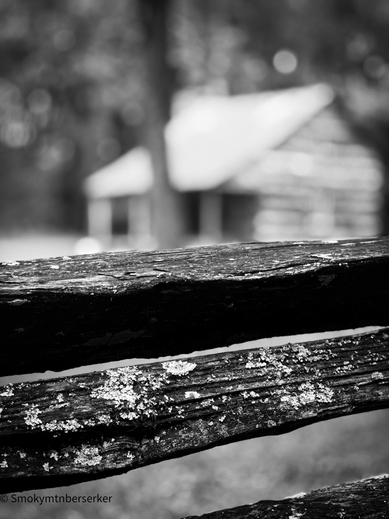 Historic cabin in Cades Cove photographed beyond a wooden fence